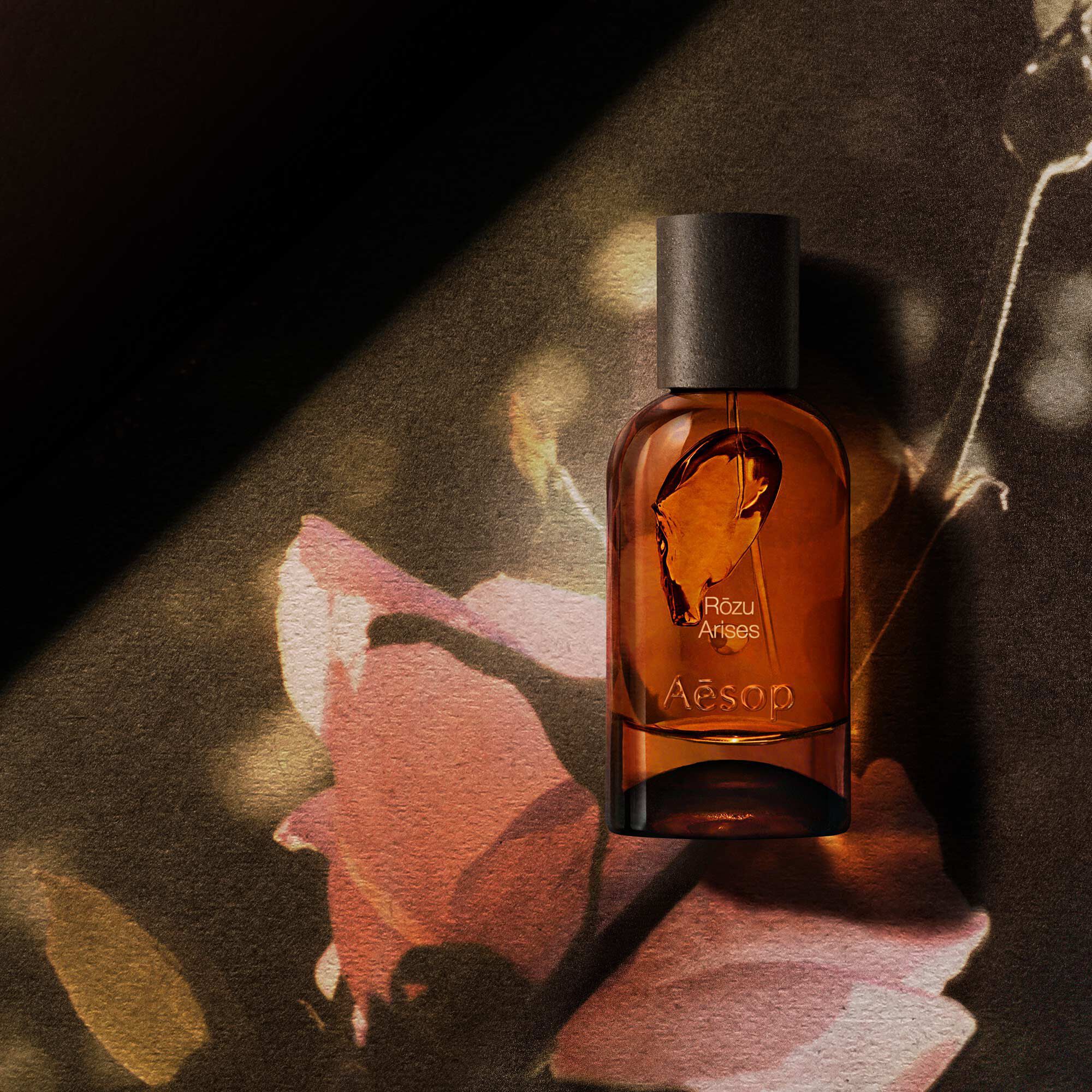 Aesop Rozu Arises bottle with a pink flower petal and curved glass.