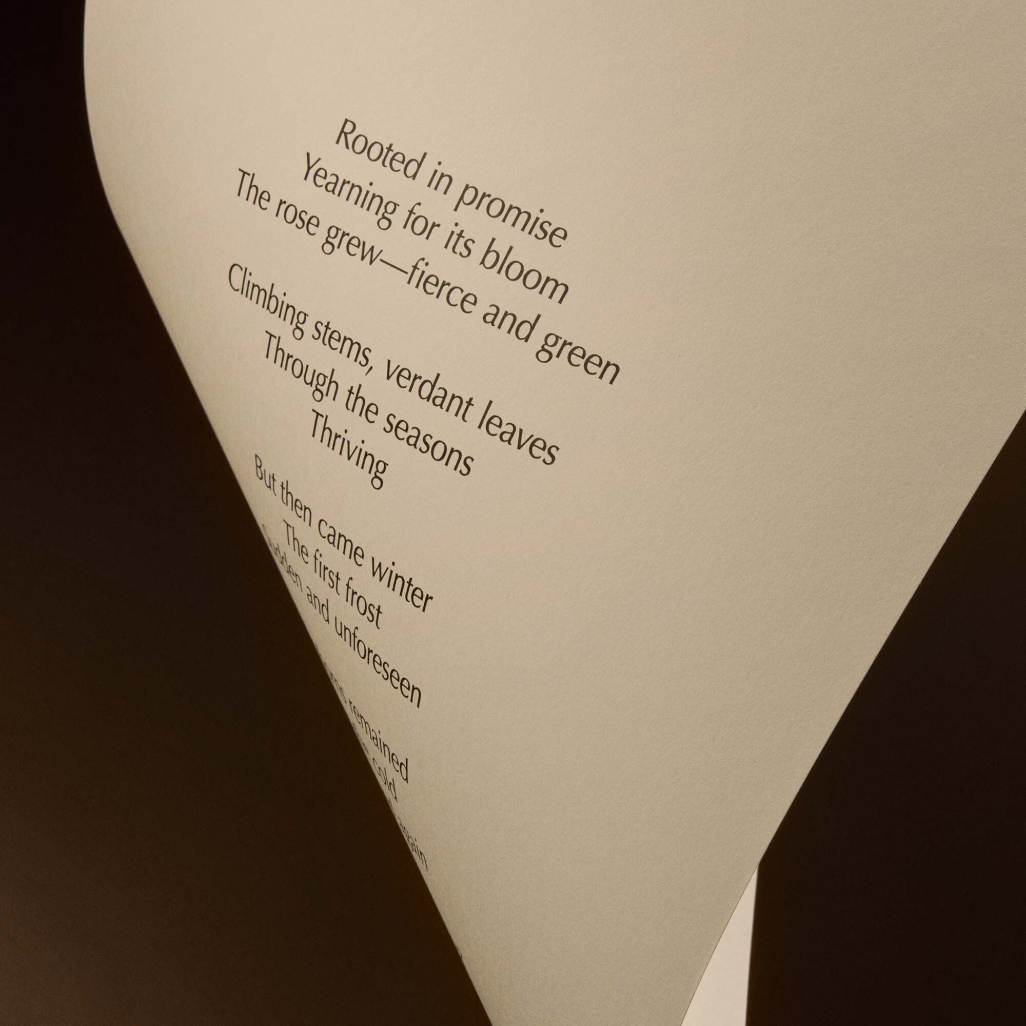 Curved cream page with printed verse against a dark brown background.