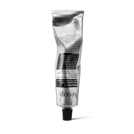 A crumpled silver tube of Aesop Resurrection Aromatique Hand Balm standing on its black cap against a white background.