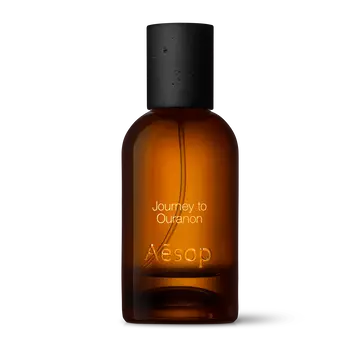 Amber glass Aesop Journey to Ouranon Eau de Parfum bottle with black cap on a white background.