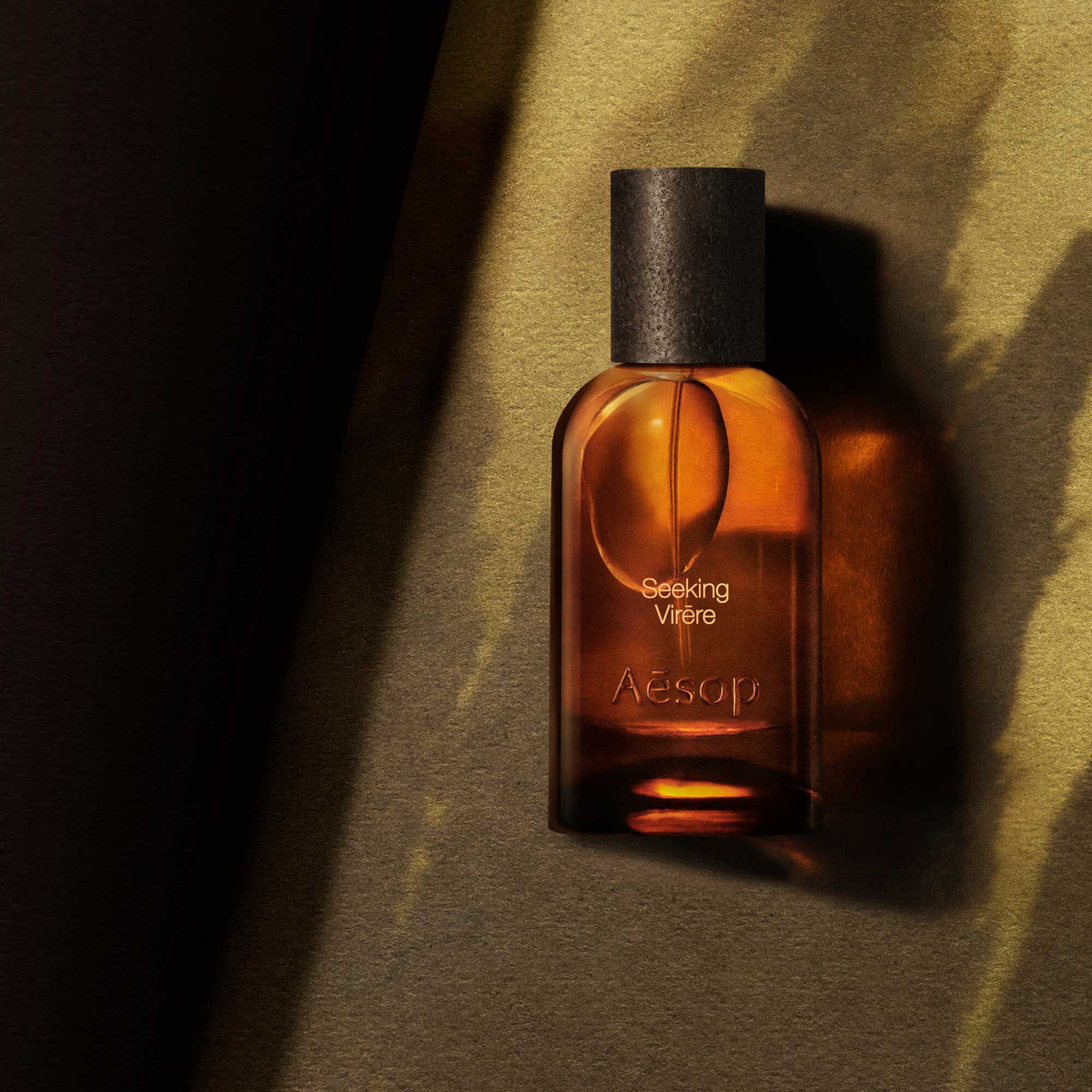 Aesop Seeking Virere bottle in shadow on a textured surface.