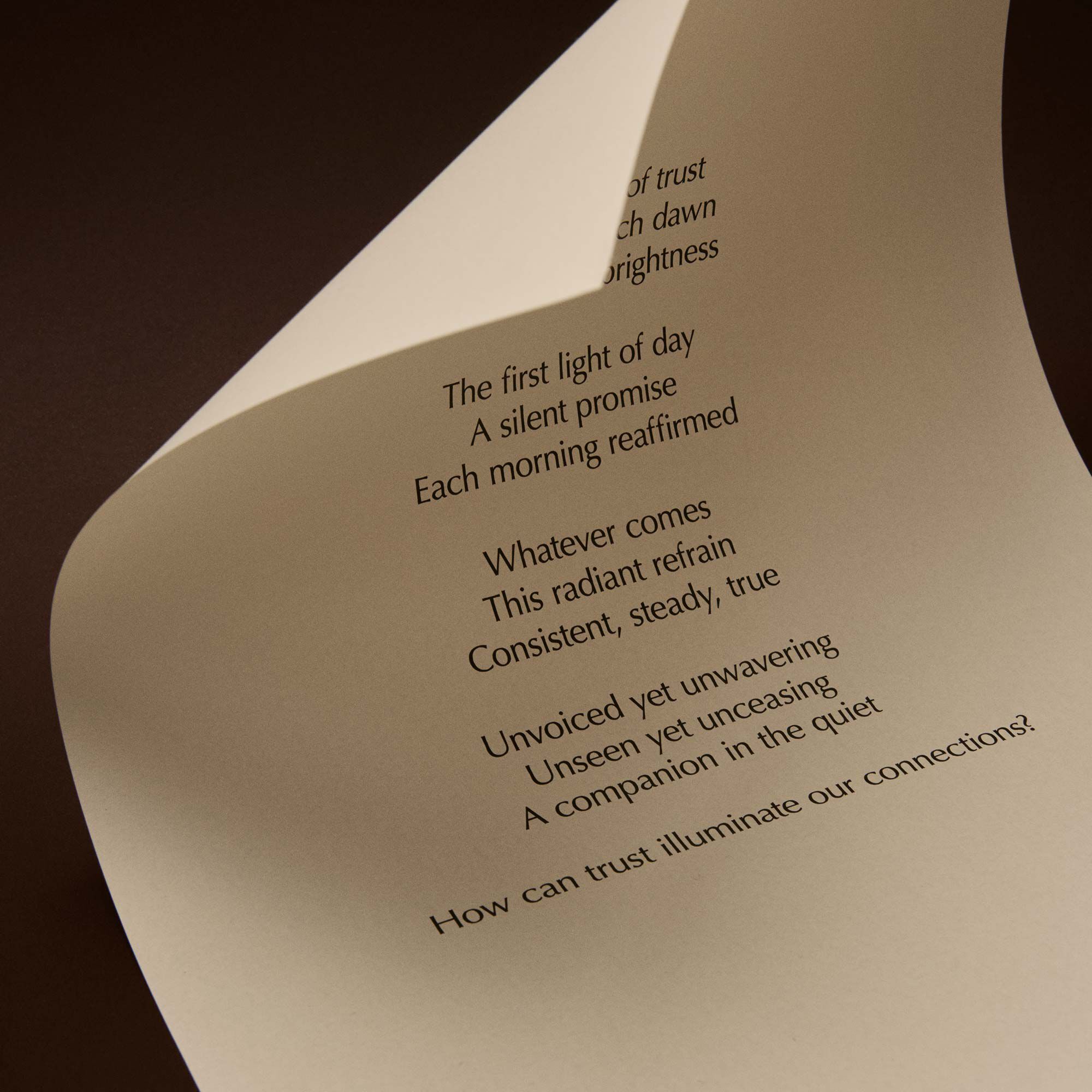 Curved cream page with printed verse against a dark brown background.
