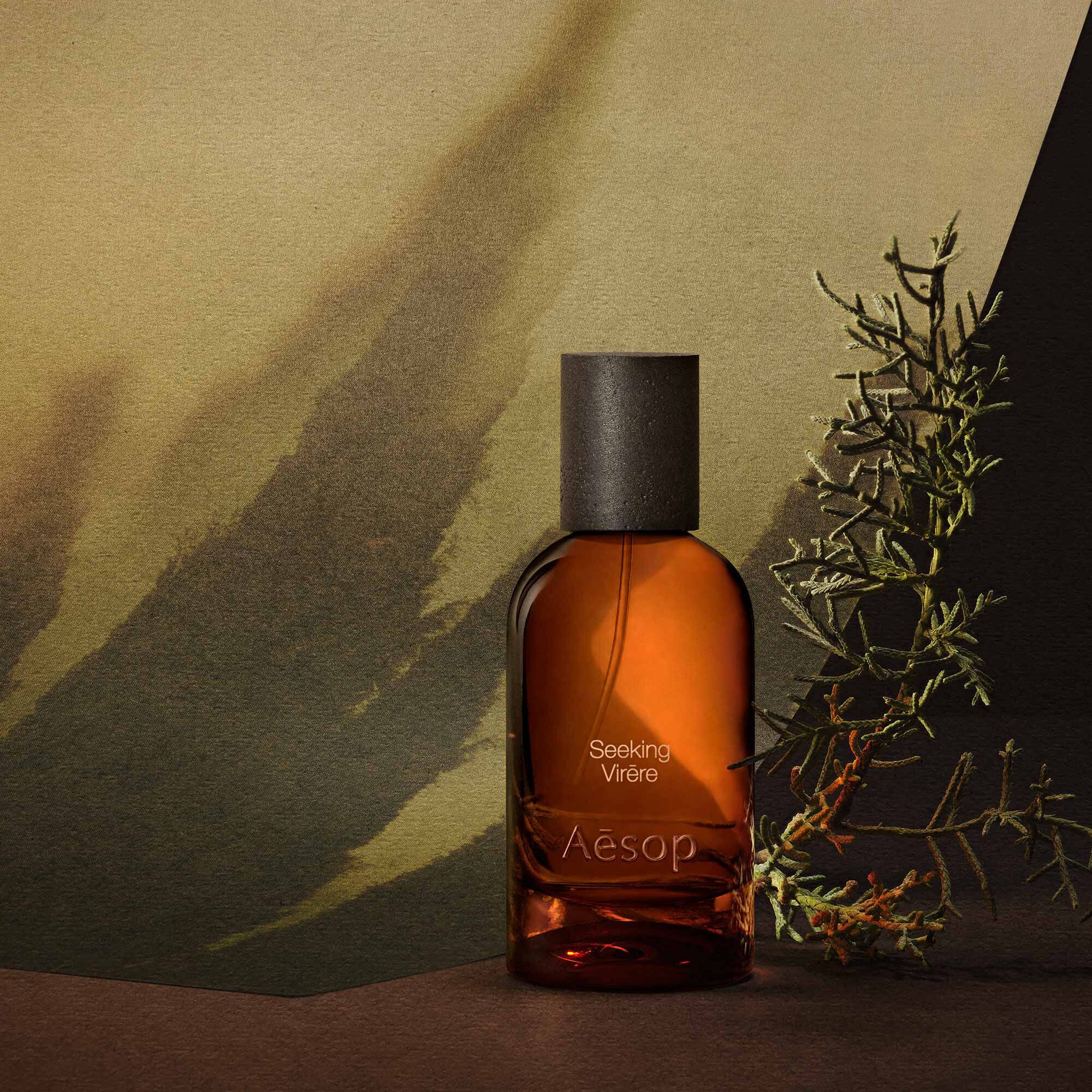Aesop Seeking Virere bottle with a woody sprig and blurred green trees.
