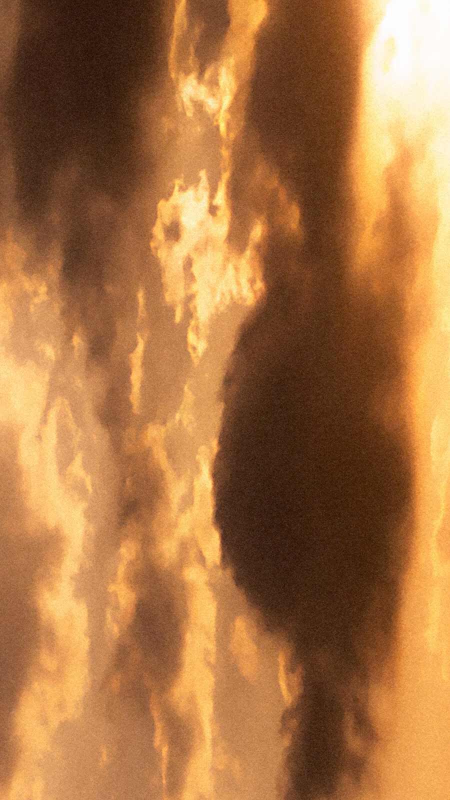 Steam or smoke rising in dramatic warm golden and amber tones against a dark background.