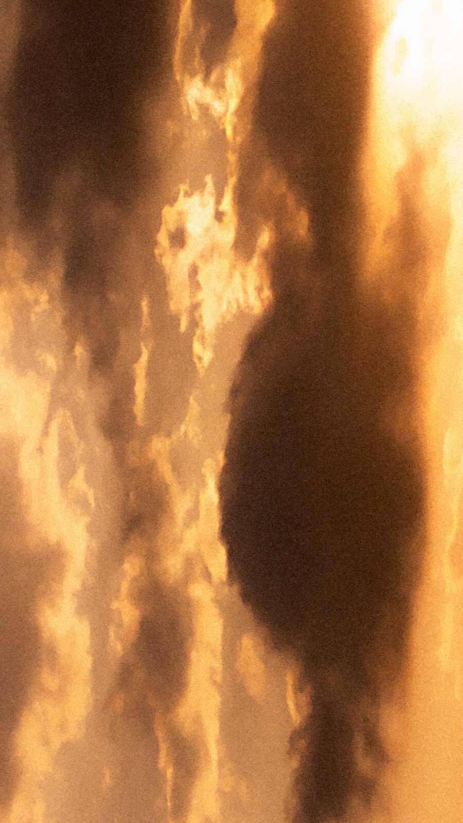 Steam or smoke rising in dramatic warm golden and amber tones against a dark background.