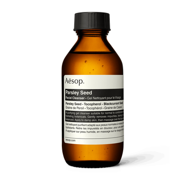 Aesop Parsley Seed Facial Cleanser in an amber bottle with a ribbed black cap and cream label on a white background.