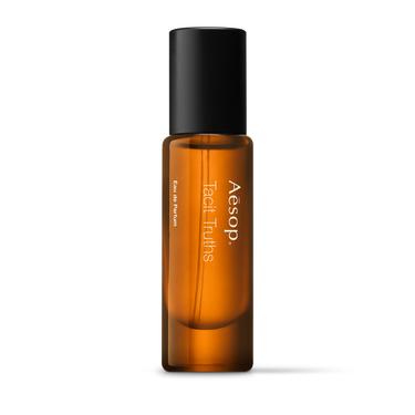 Aesop Tacit Truths in a slender amber fragrance bottle with white lettering and a tall black cap on a white background.