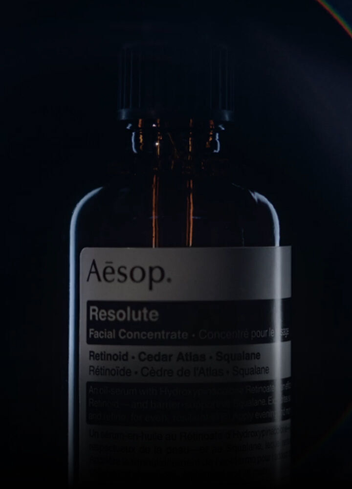 A dark glass bottle of Aesop Resolute Facial Concentrate against a black background.