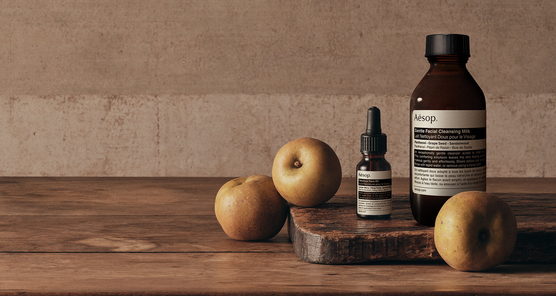 Product banner featuring Aesop skincare bottles and pears on a wooden board against a warm, rustic background.