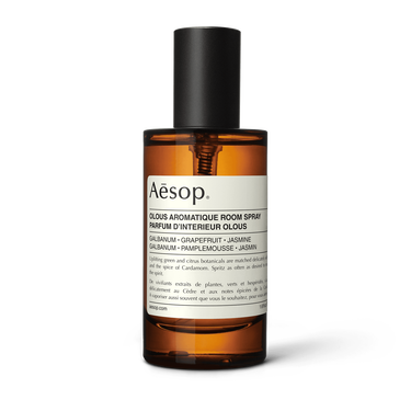Aesop Olous Aromatique Room Spray in an amber bottle with a tall black cap and cream label on a white background.