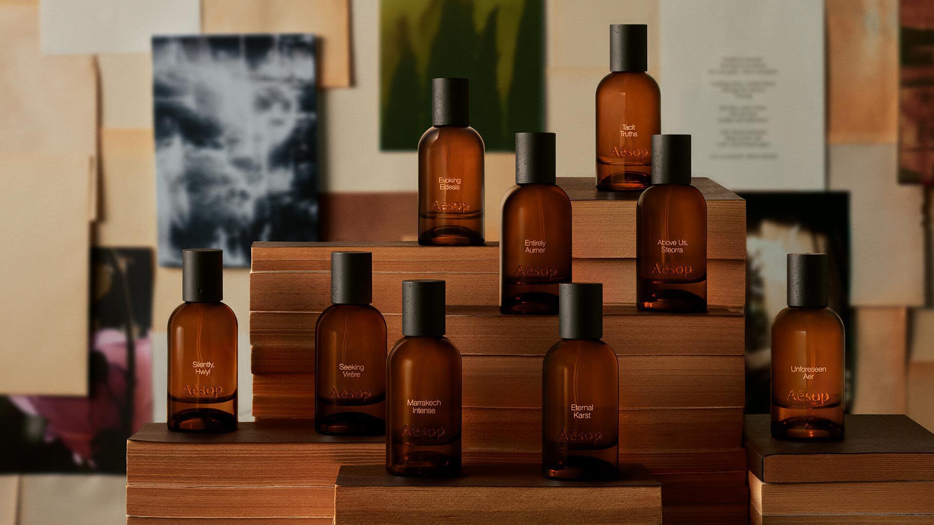 Amber Aesop fragrance bottles arranged on stepped wooden blocks before layered botanical and abstract images.