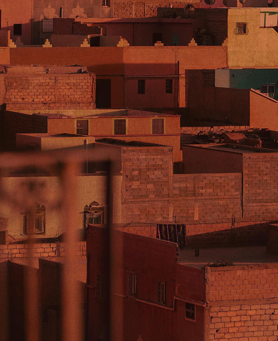 Terracotta-colored city rooftops and walls layered in warm late-day light.