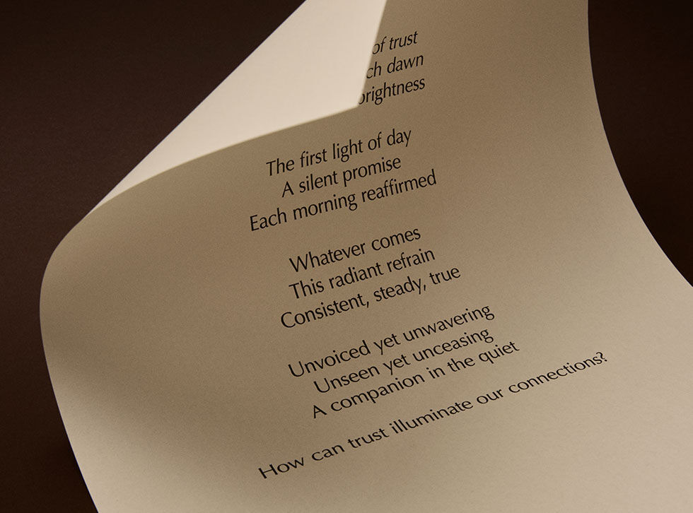 Curved cream page with printed verse against a dark brown background.