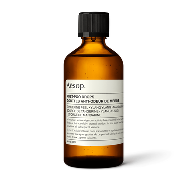 Aesop Post-Poo Drops in an amber bottle with rounded shoulders, a ribbed black cap and a cream label on a white background.